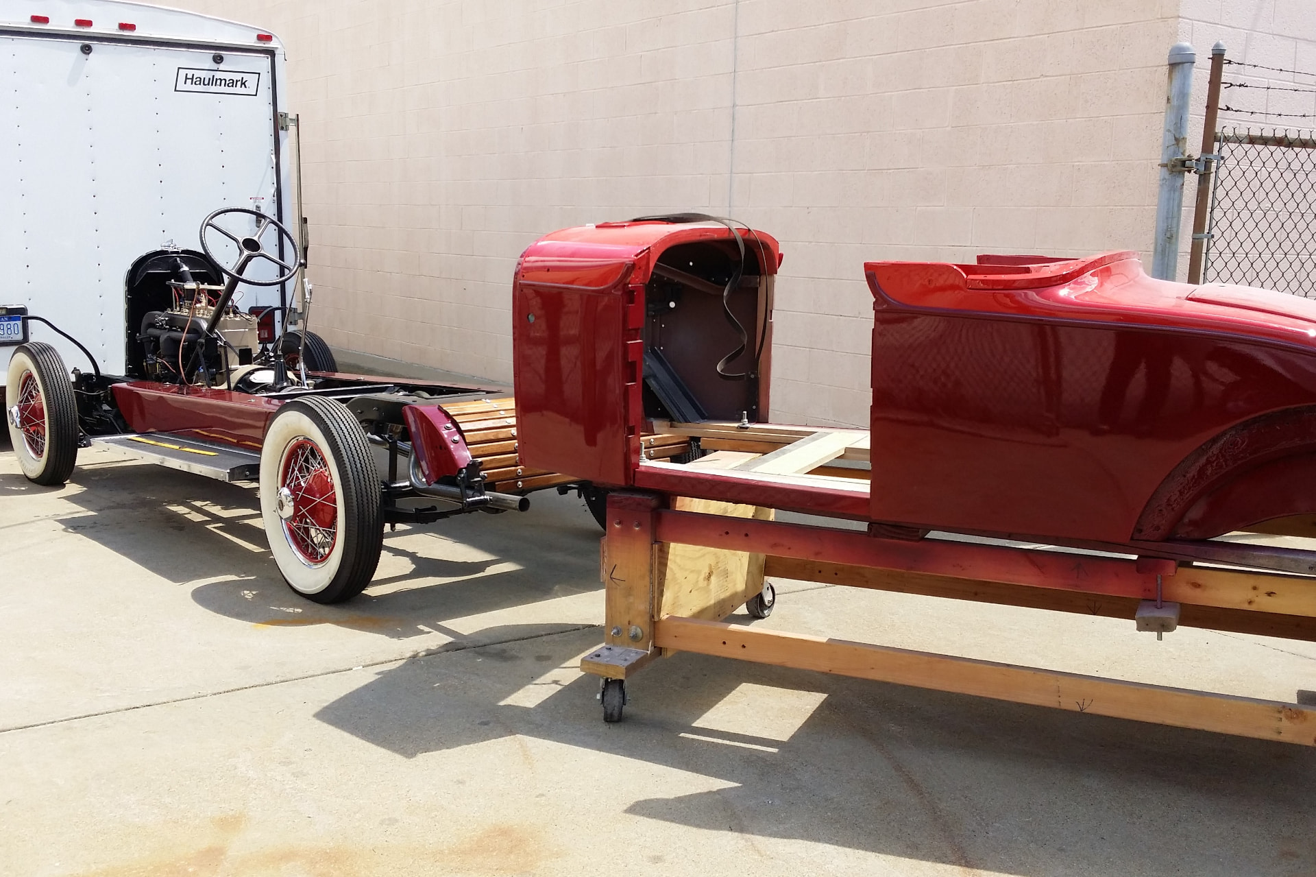 During: Auburn frame and chassis rebuild with fresh dark red paint and body panels staged alongside