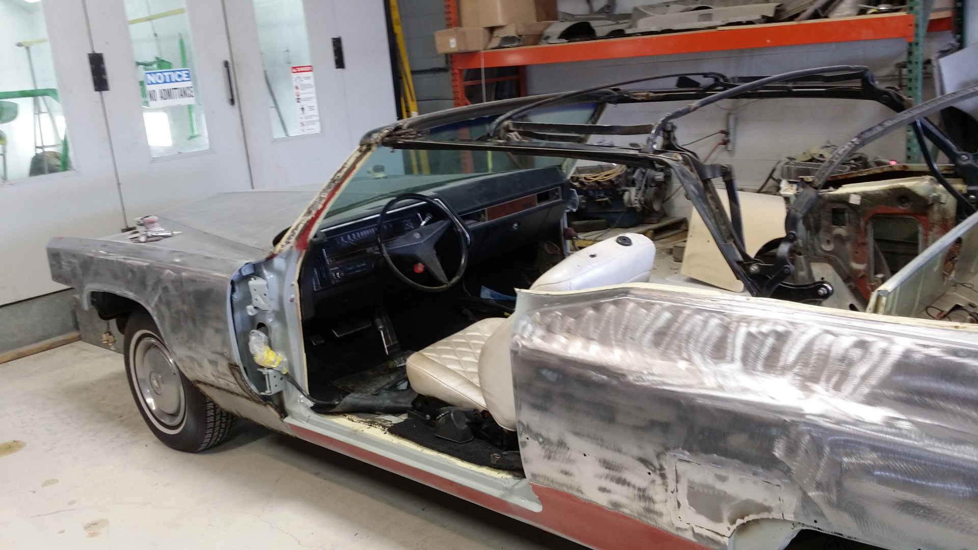 During: 1969 Cadillac DeVille convertible stripped to bare metal with the driver door and convertible top removed