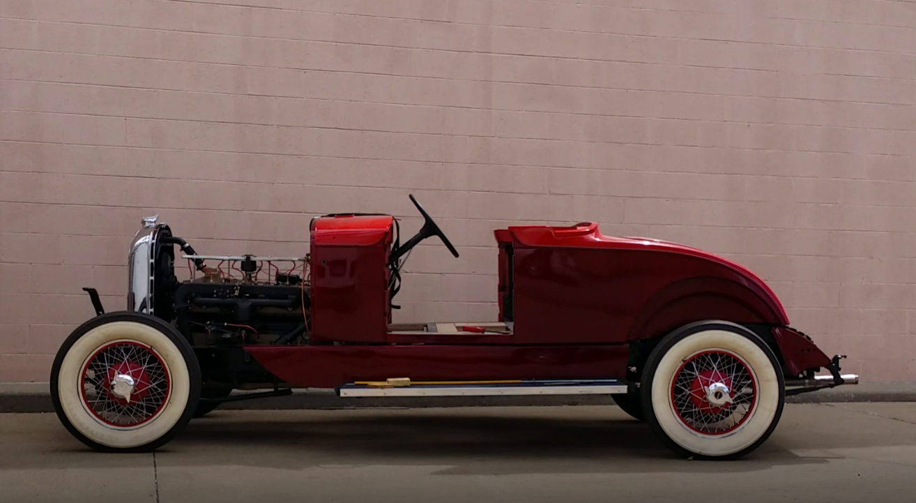 After: completed red Auburn roadster parked beside the shop wall