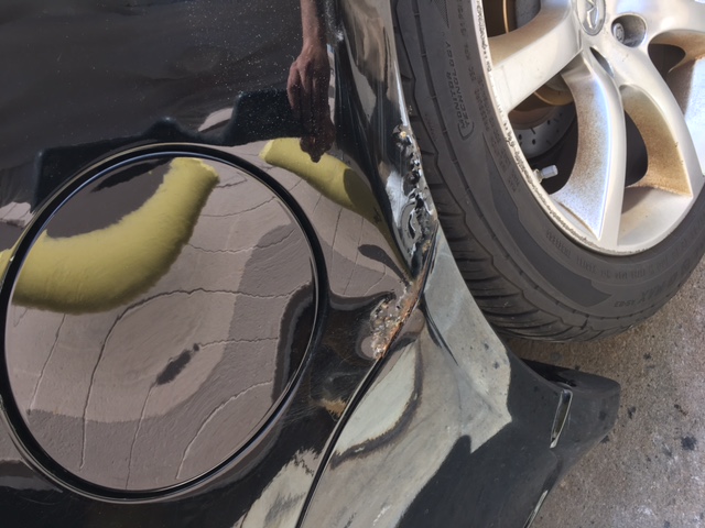 Before: 2004 Infiniti fuel door area showing rust bubbles breaking through the paint