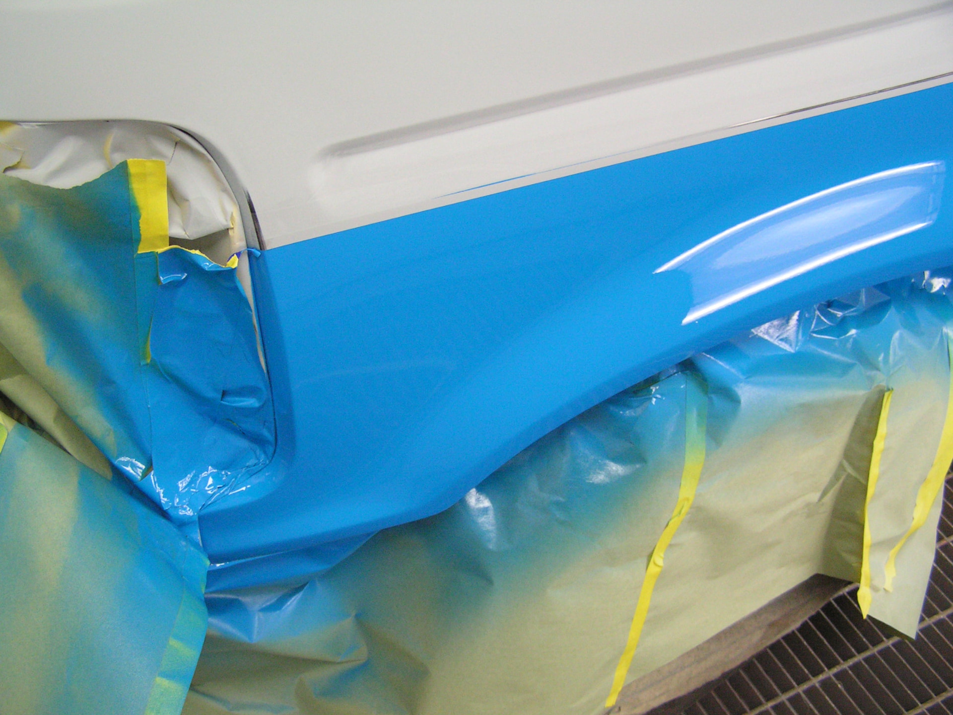 During: Ford F150 wheel arch and rocker in fresh blue paint with masking paper in place
