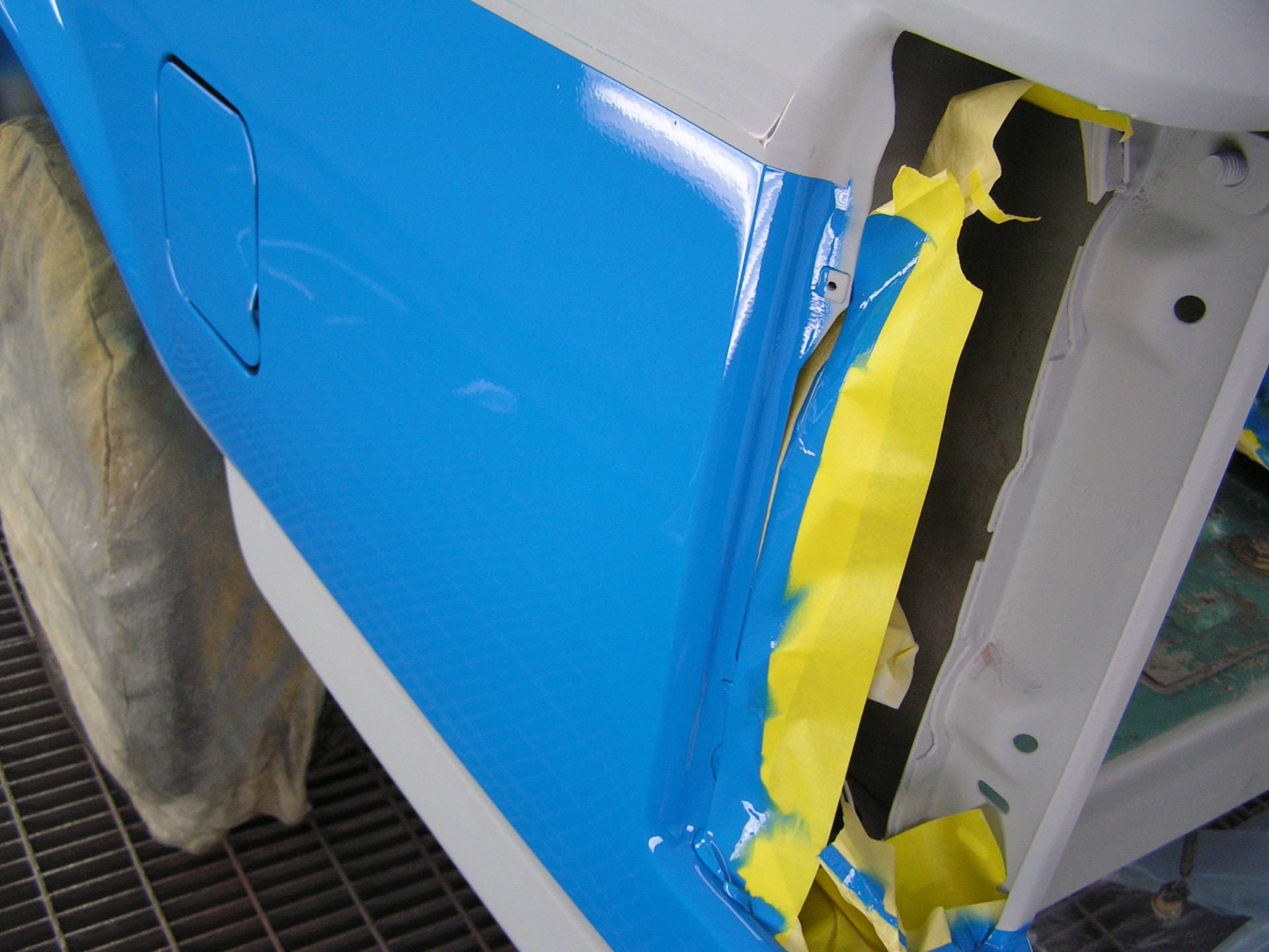 During: close-up of the Ford F150 door edge and mirror in fresh blue paint